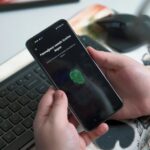 Como saber se um aplicativo é seguro antes de instalar no celular Pessoa usando sensor biométrico no celular representando segurança de aplicativos