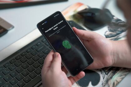 Como saber se um aplicativo é seguro antes de instalar no celular Pessoa usando sensor biométrico no celular representando segurança de aplicativos